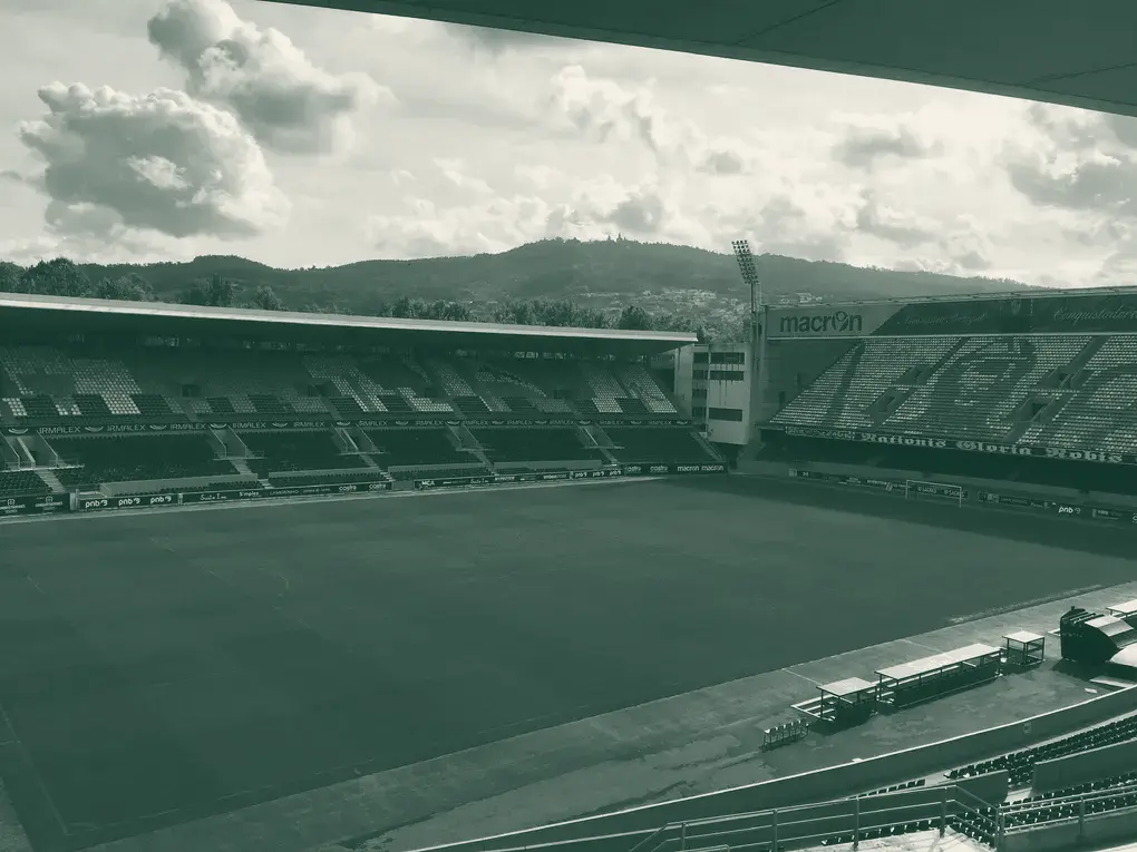 Estádio D. Afonso Henriques vazio, com bancadas pretas e brancas e colinas ao fundo