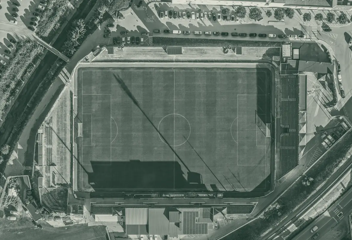 Estádio Manuel Marques em Torres Vedras visto de cima, com o relvado, a bancada coberta e a linha de comboio ao lado