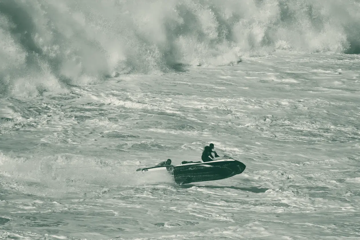 Onda grande a rebentar na Praia do Norte, na Nazaré, com uma mota de água a rebocar um surfista