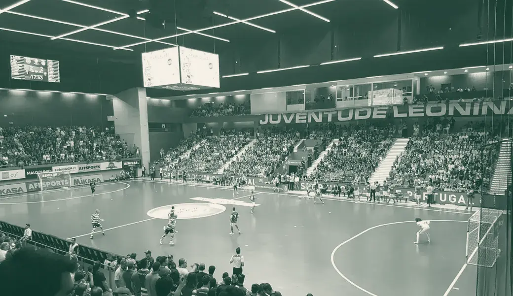 Jogo de futsal no Pavilhão João Rocha com bancadas cheias à volta do campo azul